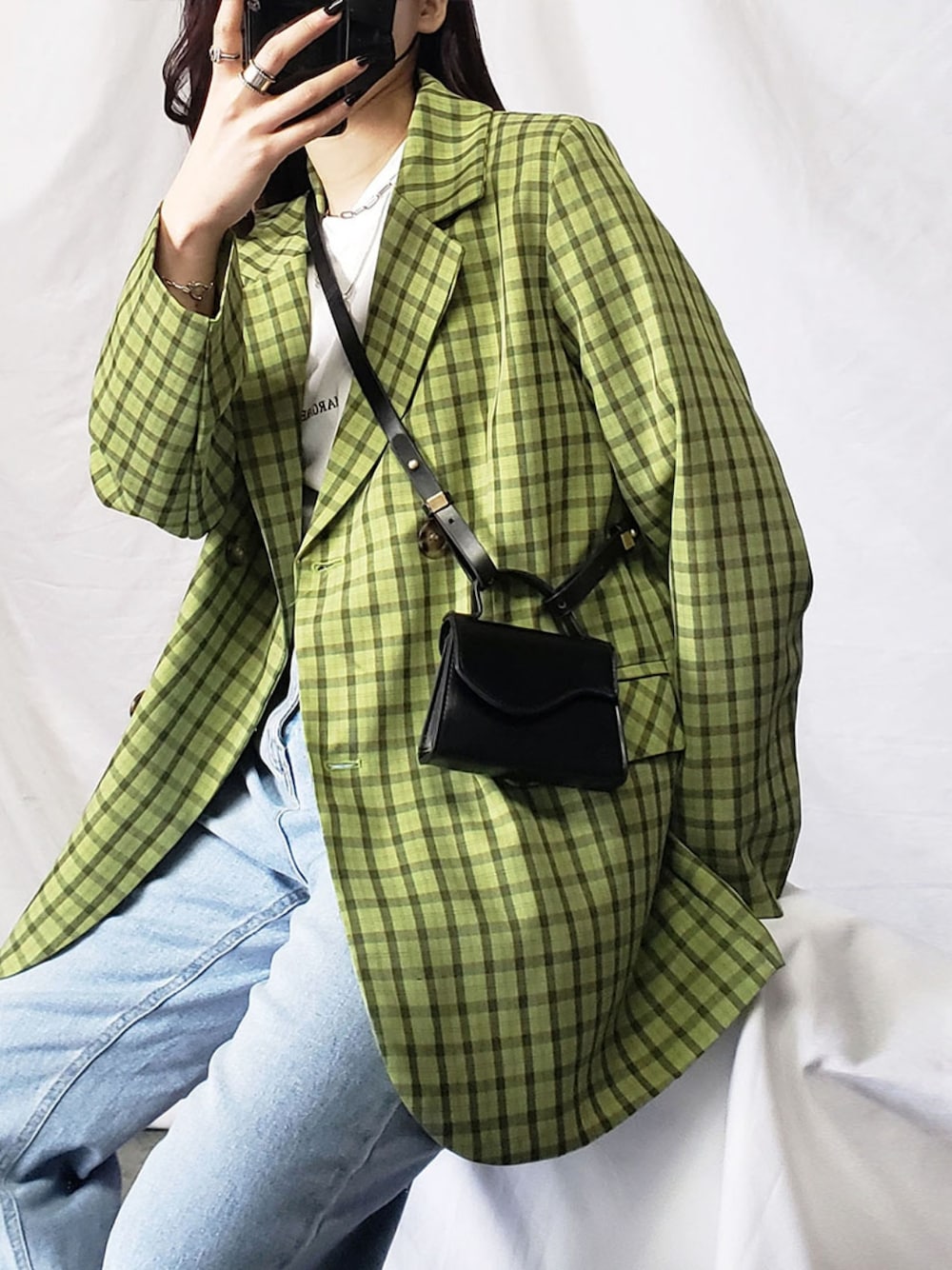 グリーン系のテーラードジャケット、ブルー系のデニムパンツ、ホワイト系のスニーカーを着用したレディースの春コーディネートの2枚目の写真