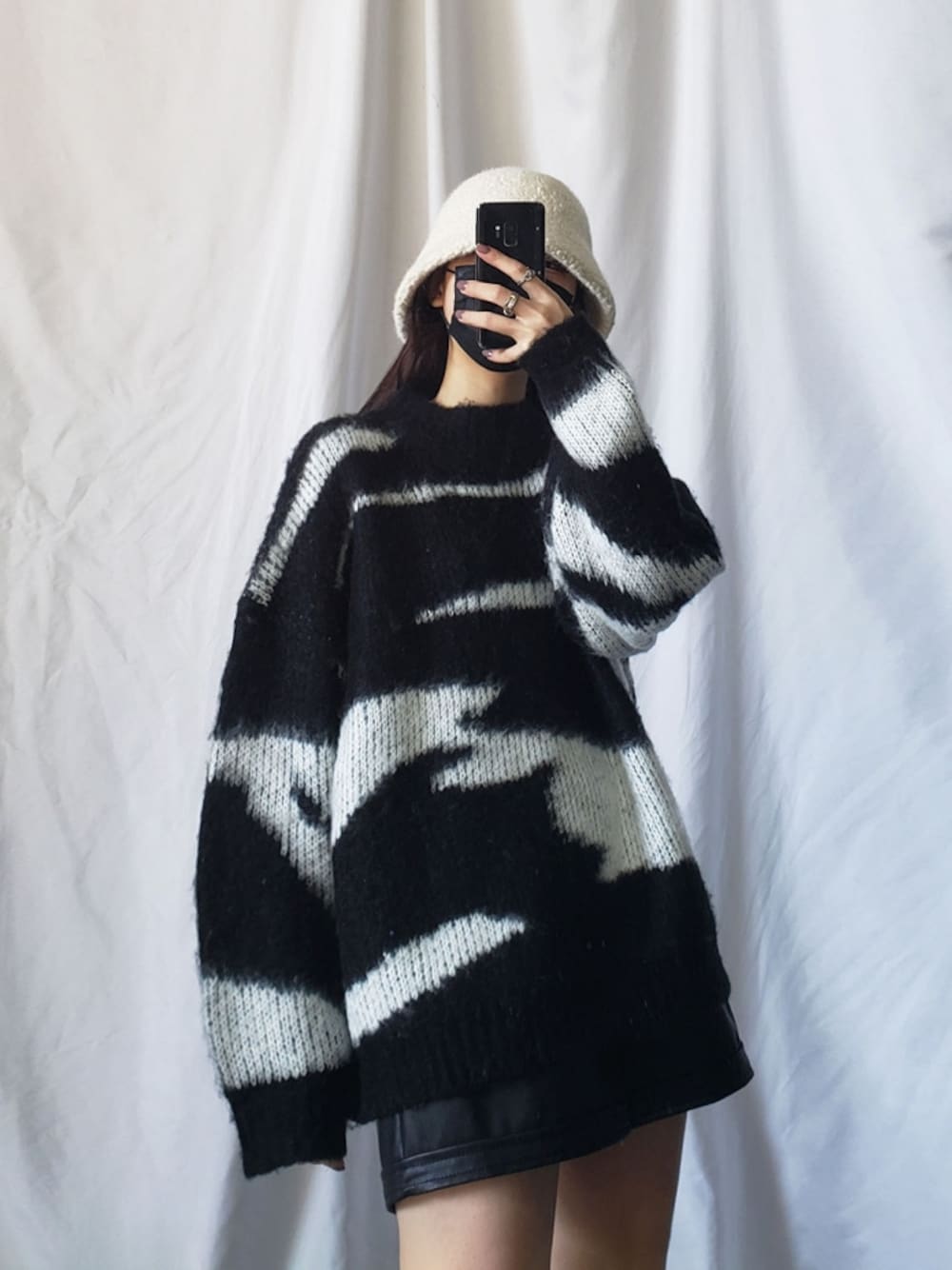 ブラック系のニット/セーター、ブラック系のその他パンツ、ホワイト系のハットを着用したレディースの冬コーディネートの1枚目の写真