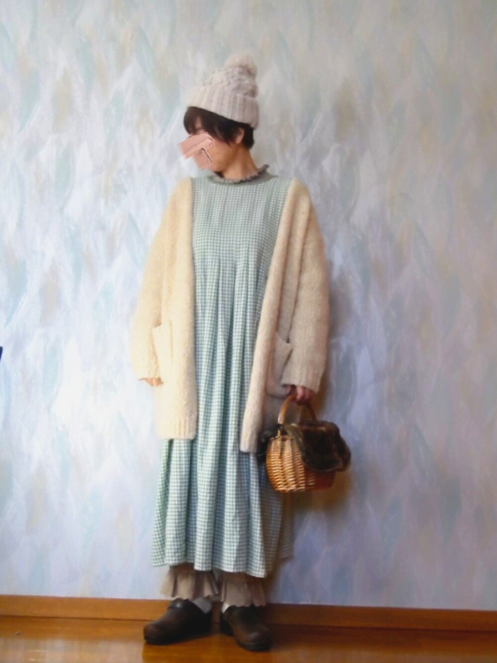 ブラウン系のかごバッグ、グリーン系のワンピース、ベージュ系のカーディガン/ボレロを着用したレディースの冬コーディネートの2枚目の写真
