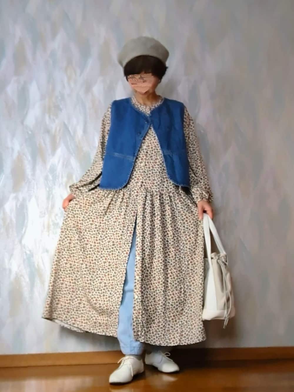 ベージュ系のワンピース、ブルー系のベスト、ブルー系のデニムパンツを着用したレディースの冬コーディネートの2枚目の写真