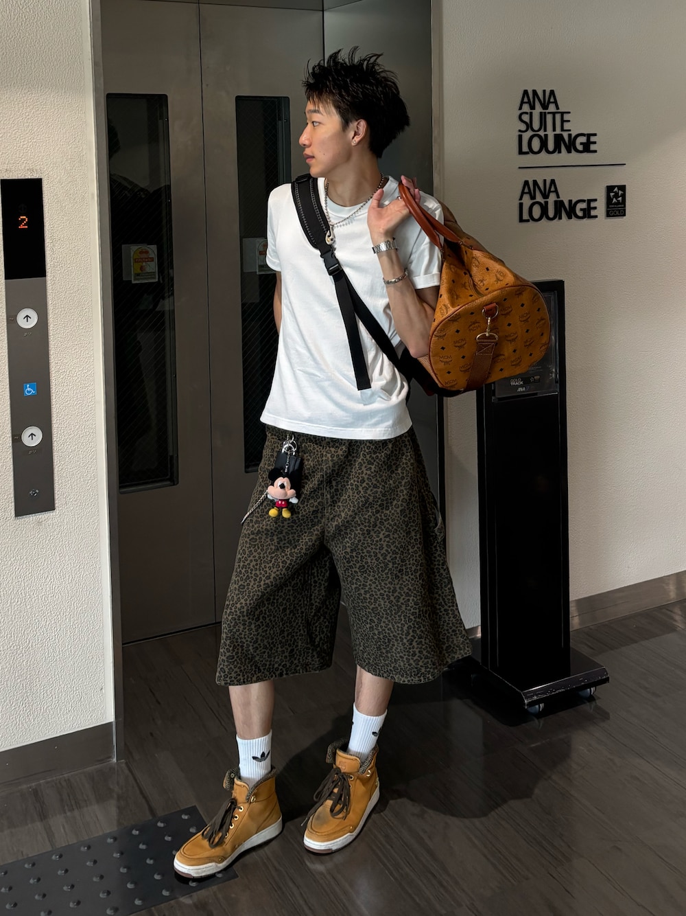 ホワイト系のTシャツ/カットソー、ブラウン系のデニムパンツ、ベージュ系のスニーカーを着用したメンズの夏コーディネートの1枚目の写真