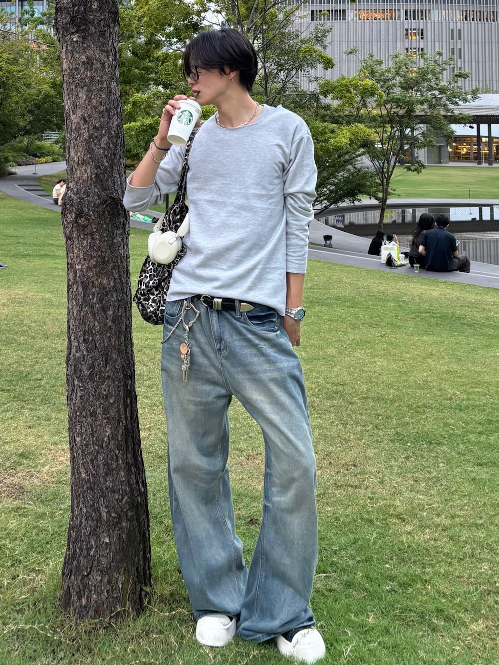 グレー系のTシャツ/カットソー、ブルー系のデニムパンツ、ブラック系のスニーカーを着用したメンズの秋コーディネートの1枚目の写真