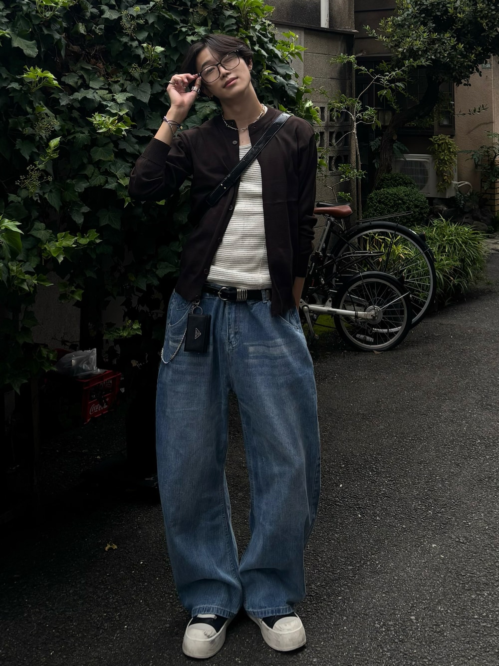 グレー系のタンクトップ、ブラウン系のカーディガン/ボレロ、ブルー系のデニムパンツを着用したメンズの秋コーディネートの1枚目の写真