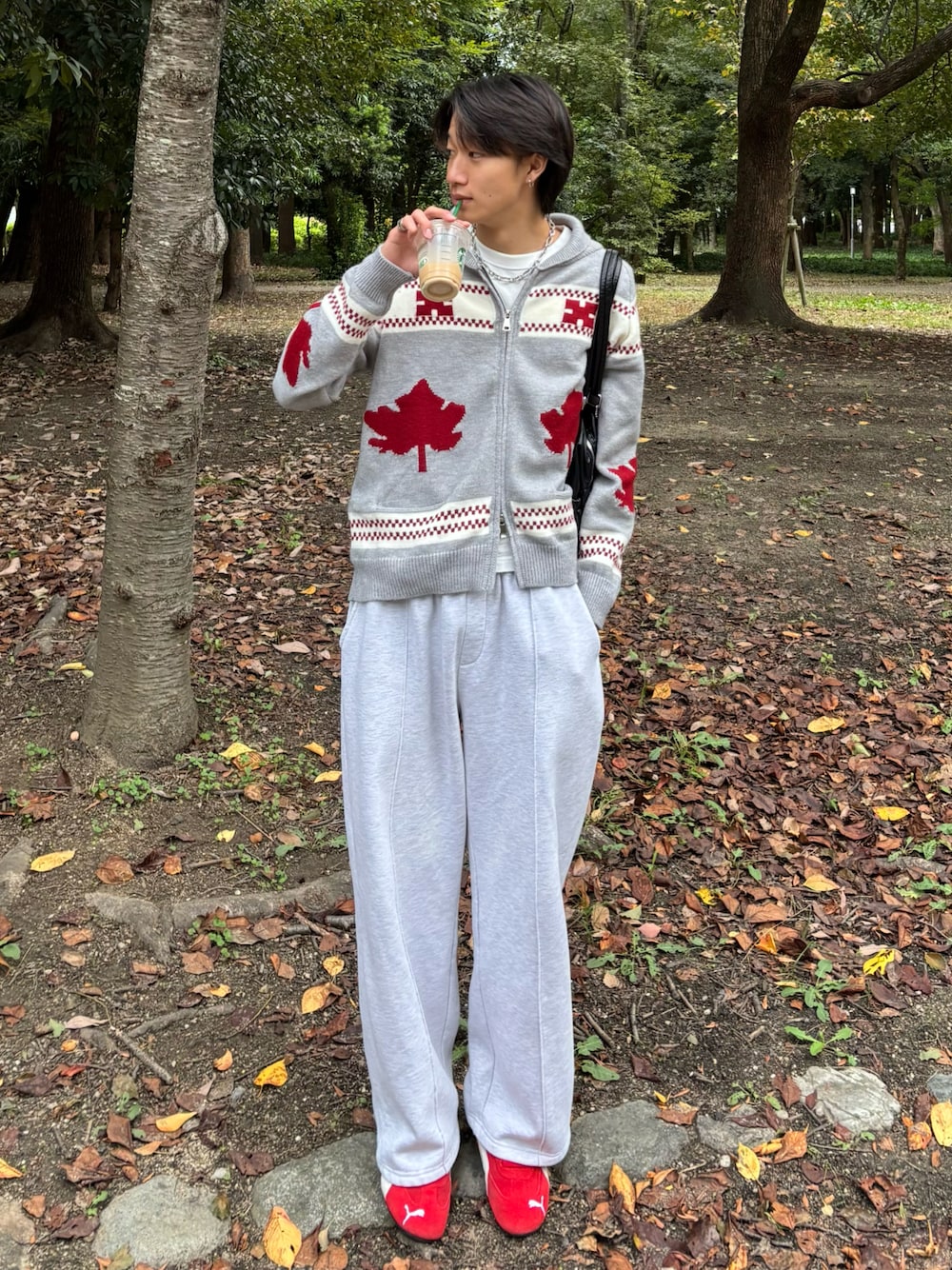 グレー系のスウェットパンツ、グレー系のニット/セーター、レッド系のスニーカーを着用したメンズの秋コーディネートの1枚目の写真