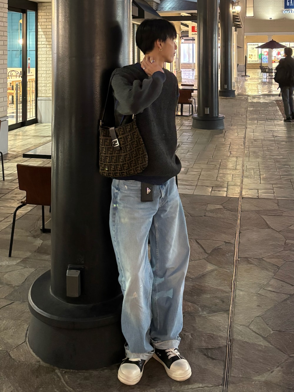 グレー系のニット/セーター、ブルー系のデニムパンツ、ブラック系のスニーカーを着用したメンズの秋コーディネートの1枚目の写真