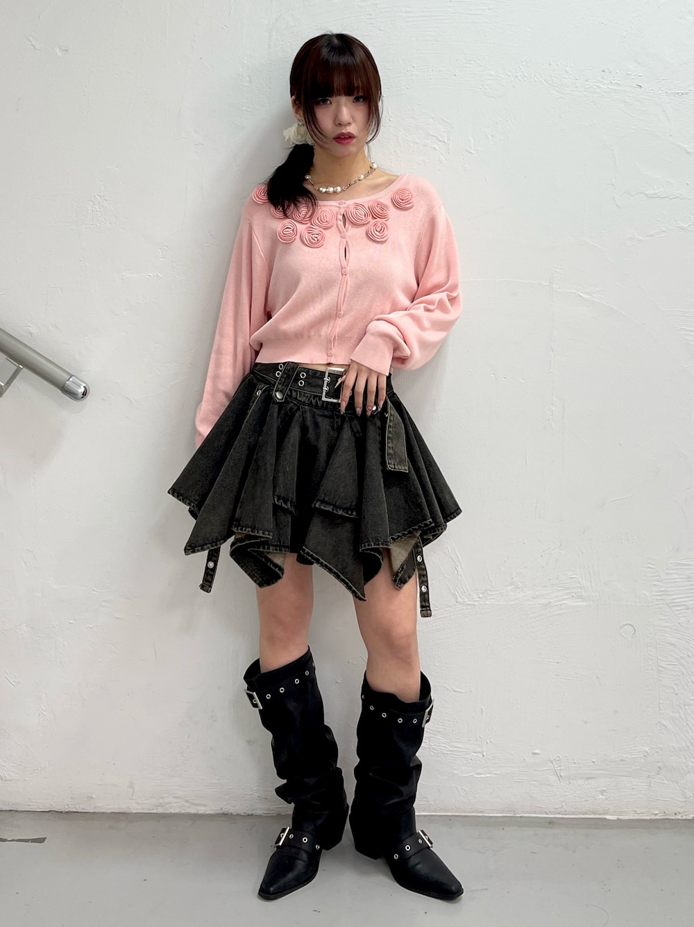 ピンク系のニット/セーター、ブラック系のデニムスカート、ブラック系のブーツを着用したレディースの春コーディネートの1枚目の写真
