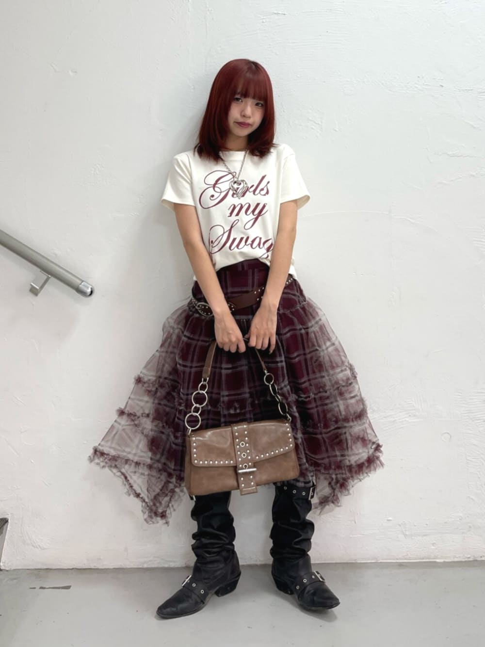 ブラウン系のハンドバッグ、ブラック系のブーツ、ホワイト系のTシャツ/カットソーを着用したレディースの夏コーディネートの1枚目の写真