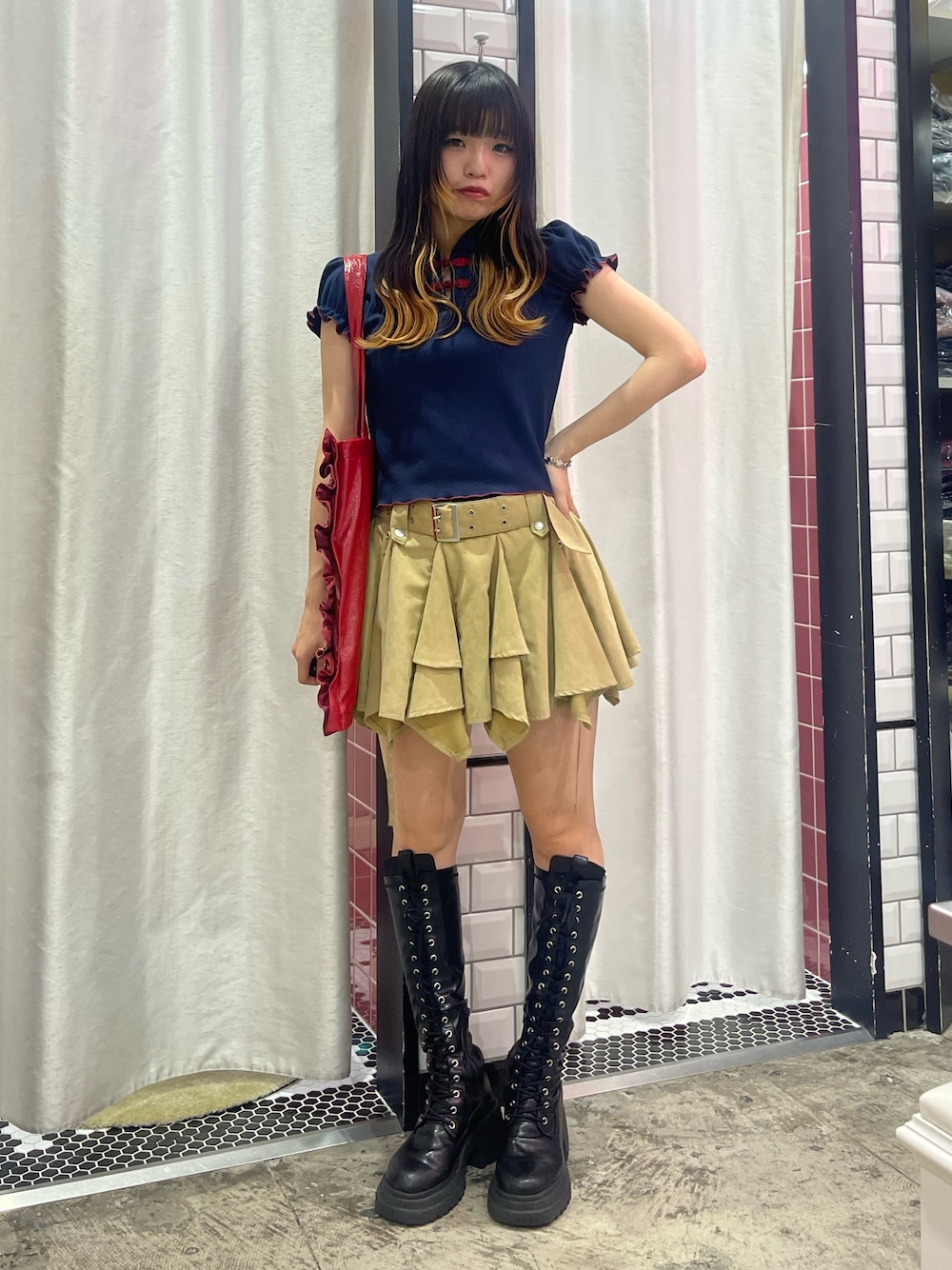 ベージュ系のスカート、ブルー系のポロシャツ、レッド系のトートバッグを着用したレディースの夏コーディネートの1枚目の写真