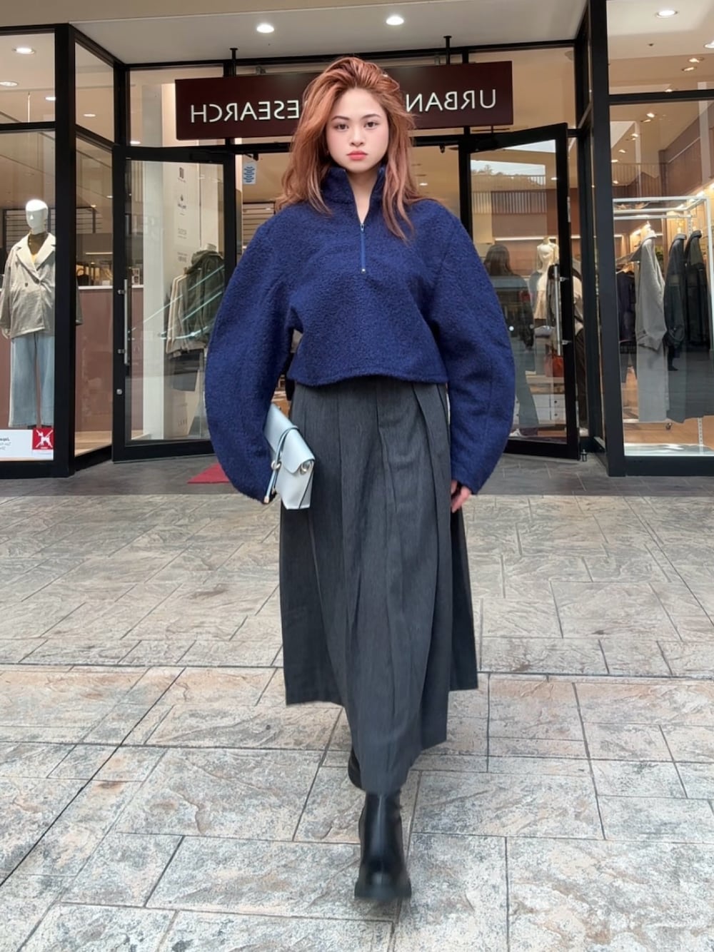 グレー系のショルダーバッグ、ブラック系のスカート、ブラック系のブーツを着用したレディースの秋コーディネートの1枚目の写真