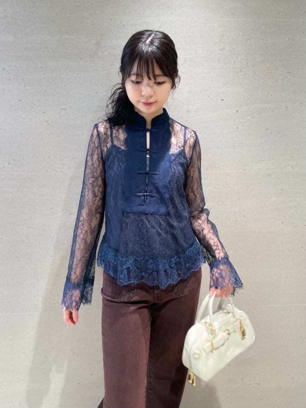 ブラウン系のデニムパンツ、ホワイト系のボストンバッグを着用したレディースの秋コーディネートの1枚目の写真