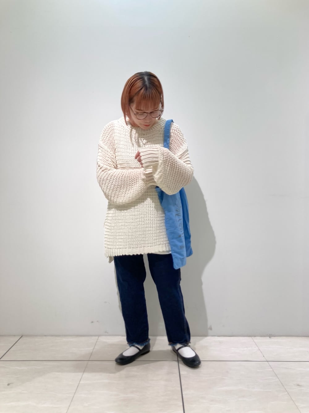 ブルー系のトートバッグ、ホワイト系のニット/セーター、ホワイト系のタンクトップを着用したレディースの春コーディネートの2枚目の写真