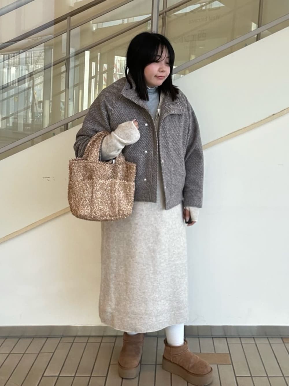 ベージュ系のワンピース、ブラウン系のブルゾン、グレー系のTシャツ/カットソーを着用したレディースの冬コーディネートの1枚目の写真