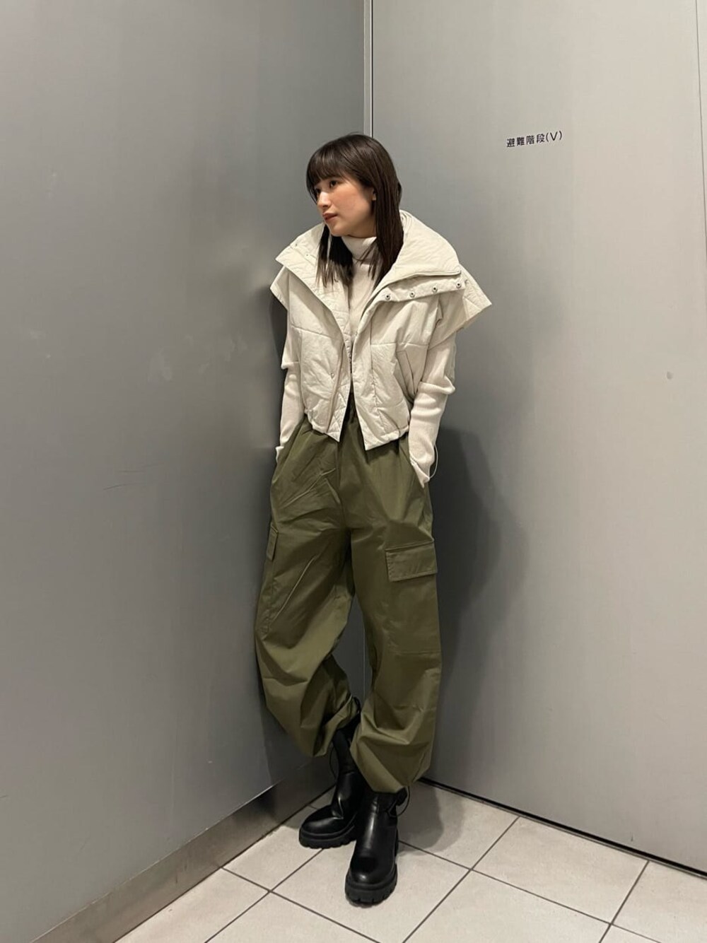 ホワイト系のダウンベスト、ブラック系のブーツ、ホワイト系のニット/セーターを着用したレディースの秋コーディネートの1枚目の写真