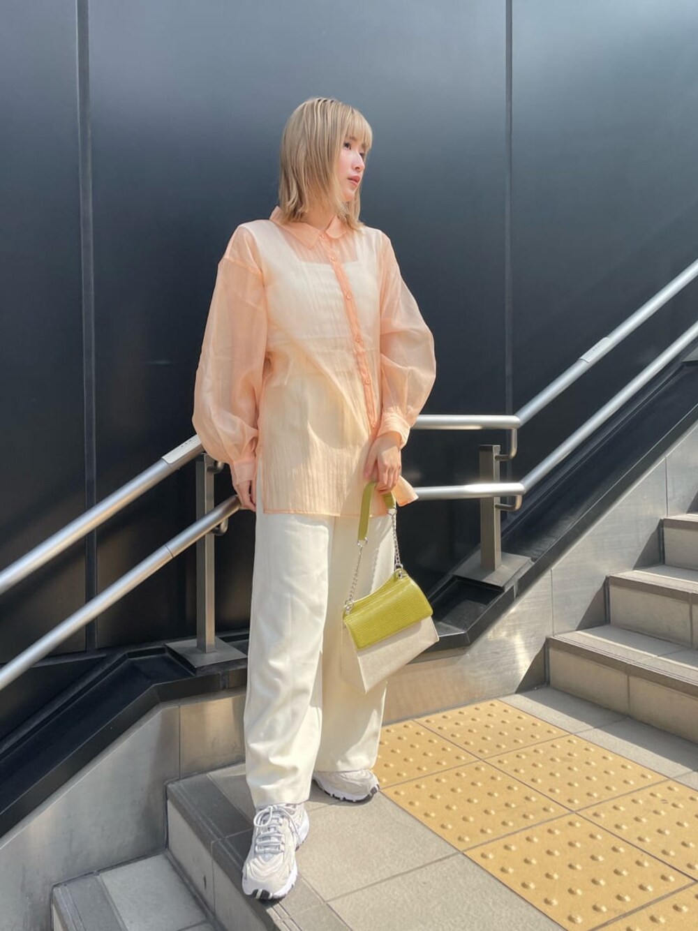 ホワイト系のスラックス、ホワイト系のハンドバッグ、ホワイト系のタンクトップを着用したレディースの春コーディネートの1枚目の写真