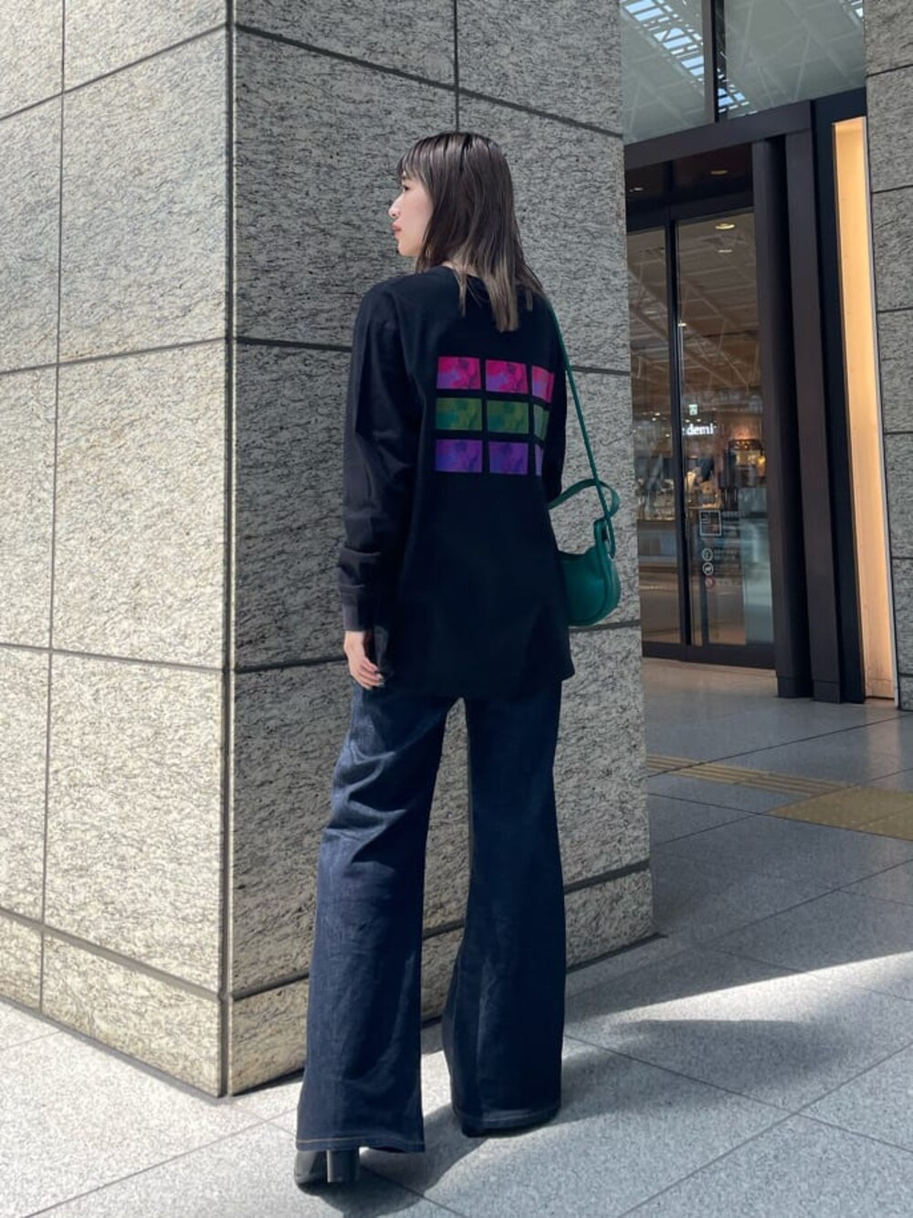 グリーン系のハンドバッグ、ブラック系のブーツ、ブラック系のTシャツ/カットソーを着用したレディースの夏コーディネートの1枚目の写真
