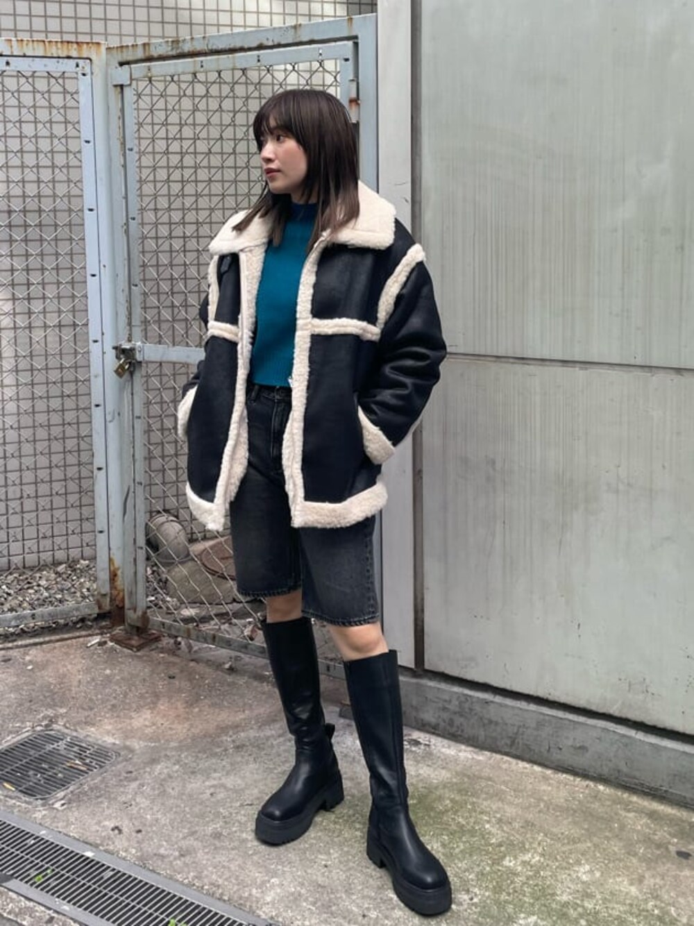 ブラック系のブーツ、ブルー系のニット/セーター、ブラック系のムートンコートを着用したレディースの秋コーディネートの1枚目の写真