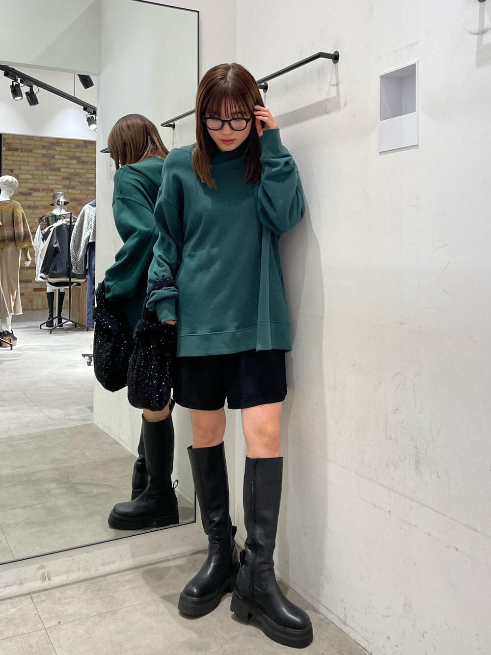グリーン系のパーカー、ブラック系のブーツを着用したレディースの秋コーディネートの1枚目の写真