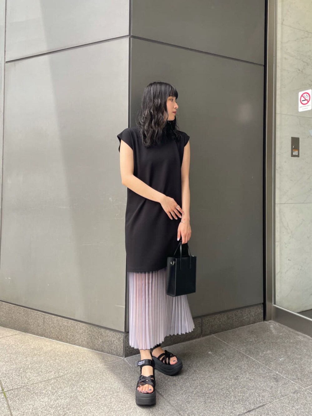 ブルー系のスカート、ブラック系のワンピース、ブラック系のサンダルを着用したレディースの夏コーディネートの1枚目の写真
