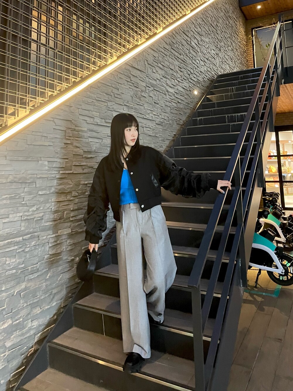 ブラック系のブルゾン、グレー系のスラックス、ブルー系のニット/セーターを着用したレディースの春コーディネートの1枚目の写真