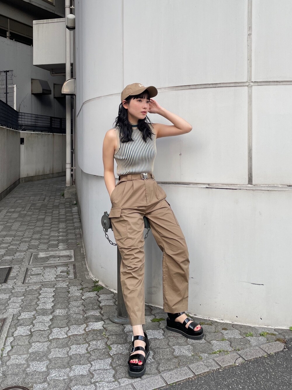 グリーン系のカーゴパンツ、ベージュ系のニット/セーター、ベージュ系のキャップを着用したレディースの春コーディネートの1枚目の写真