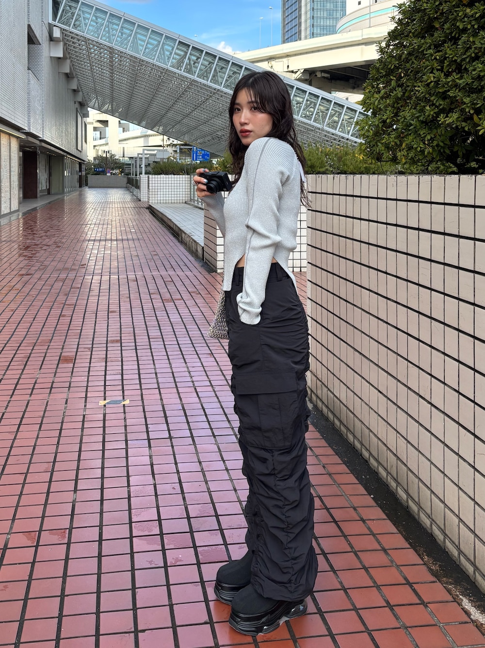 シルバー系のショルダーバッグ、ブラック系のデニムパンツ、グレー系のニット/セーターを着用したレディースの春コーディネートの1枚目の写真