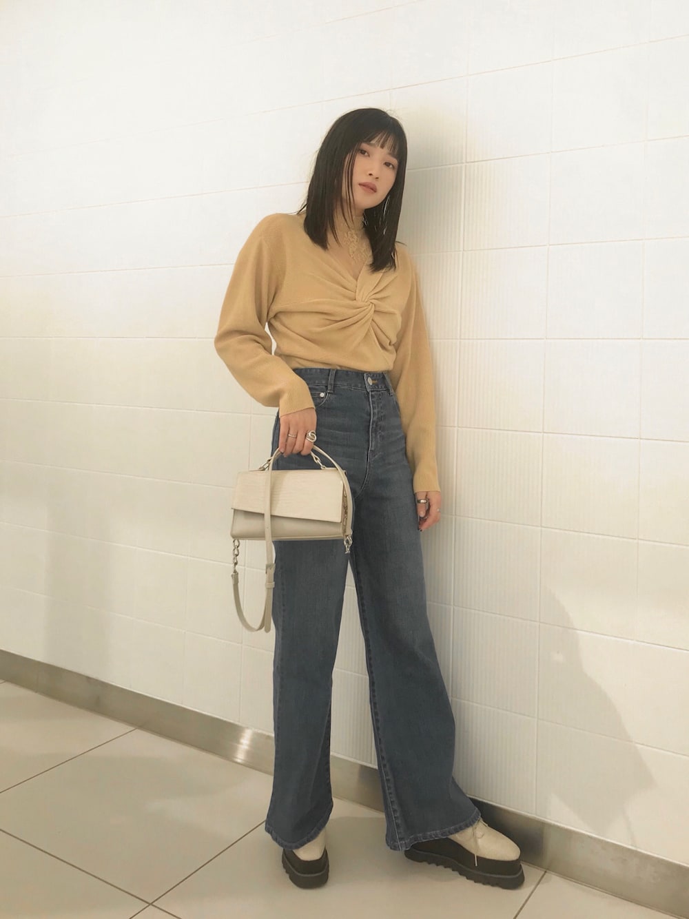 ホワイト系のローファー、ブルー系のデニムパンツ、ホワイト系のハンドバッグを着用したレディースの冬コーディネートの1枚目の写真