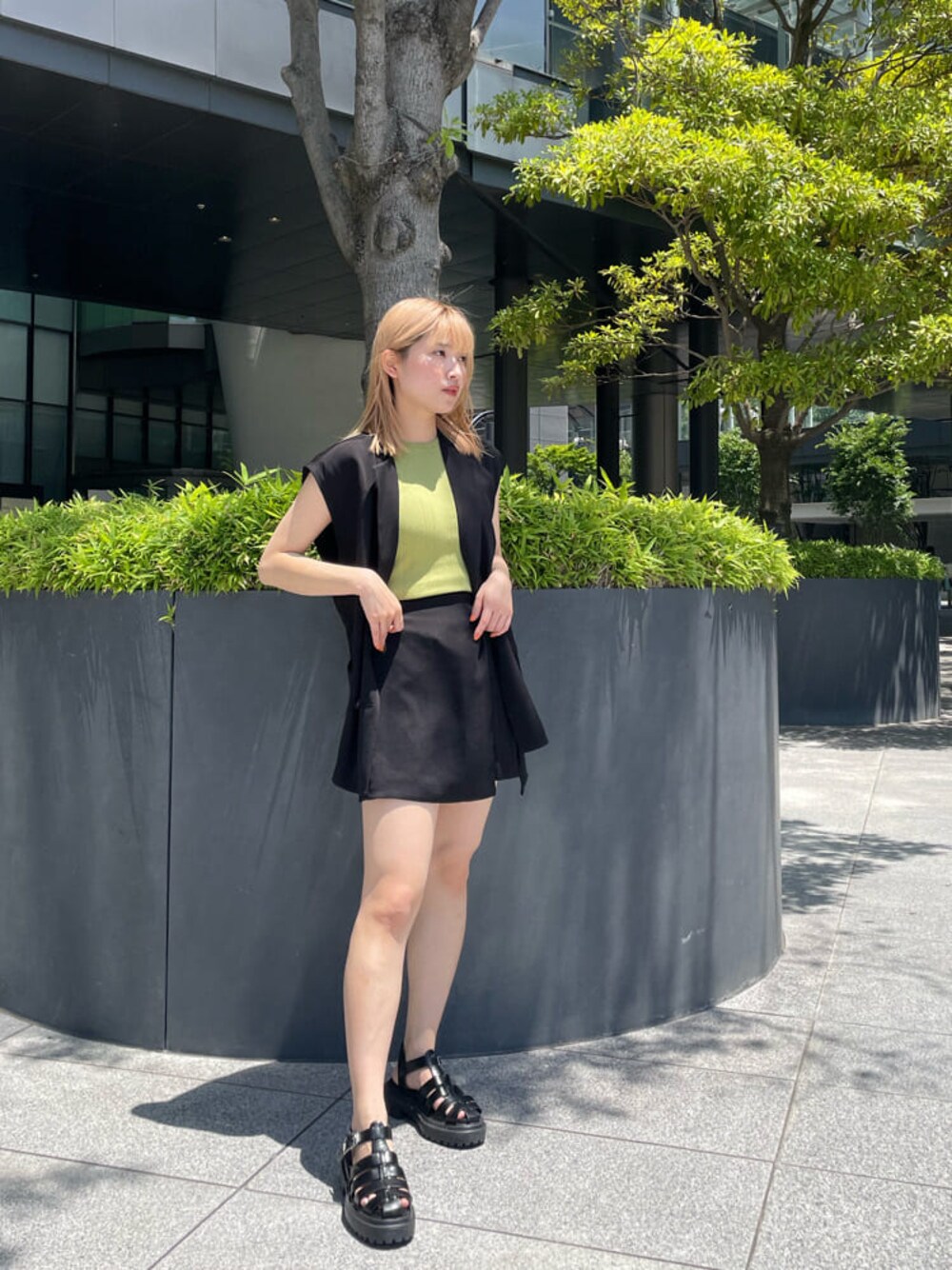 ブラック系のベスト、ブラック系のスラックス、グリーン系のタンクトップを着用したレディースの夏コーディネートの1枚目の写真