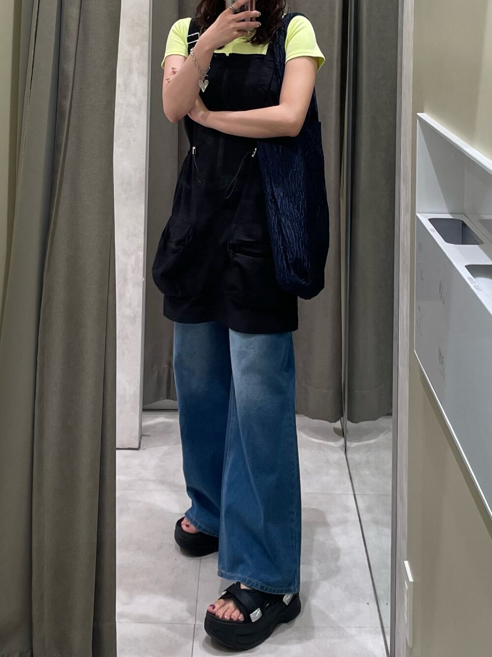 ブラック系のワンピース、ブルー系のデニムパンツ、ブラック系のサンダルを着用したレディースの春コーディネートの1枚目の写真