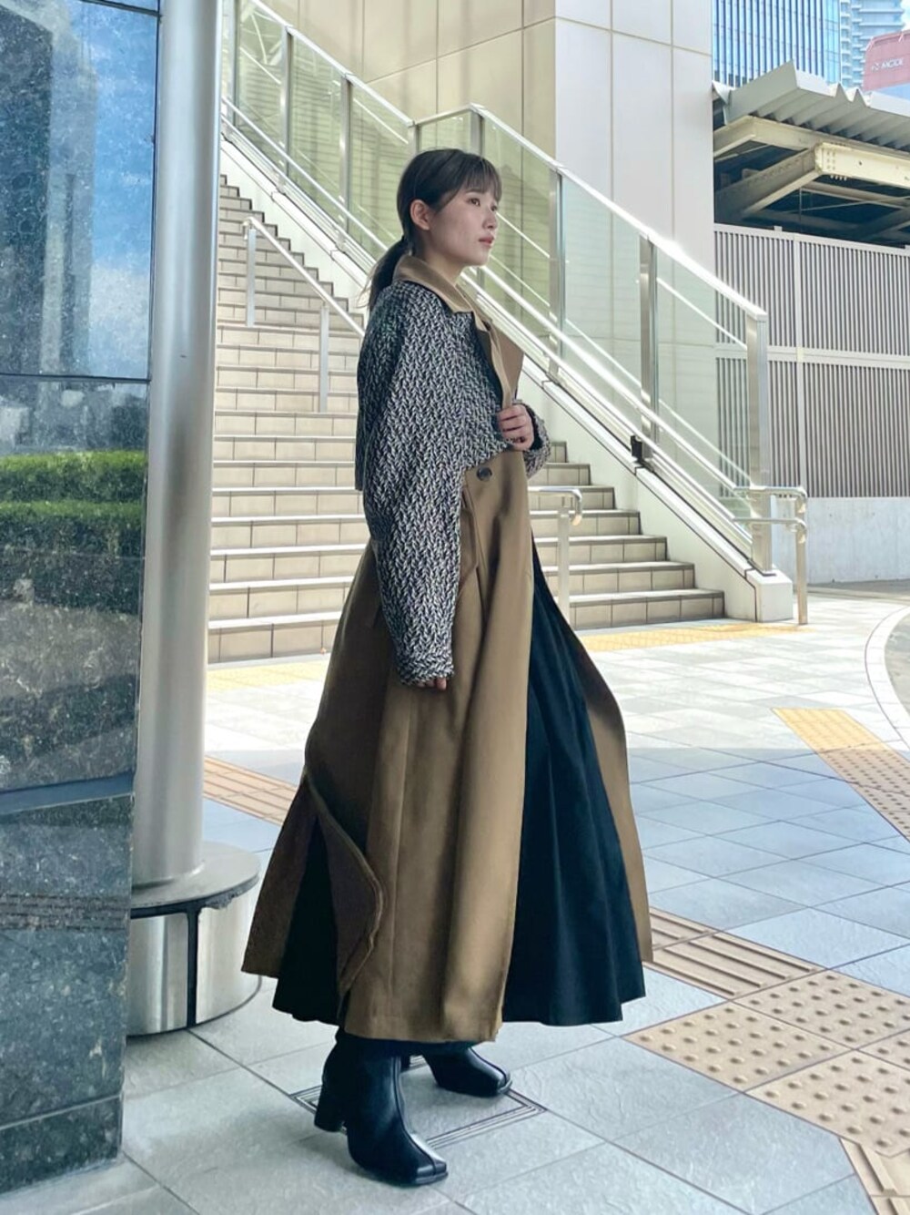 ブラック系のシャツ/ブラウス、ブラック系のハンドバッグ、ブラウン系のトレンチコートを着用したレディースの夏コーディネートの1枚目の写真