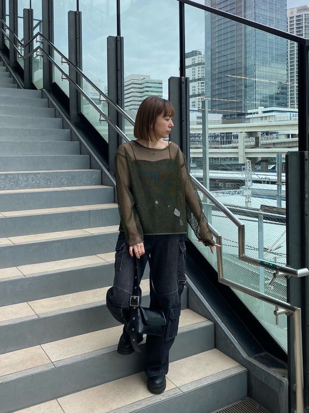 グリーン系のTシャツ/カットソー、ブラック系のデニムパンツ、ブラック系のショルダーバッグを着用したレディースの冬コーディネートの1枚目の写真