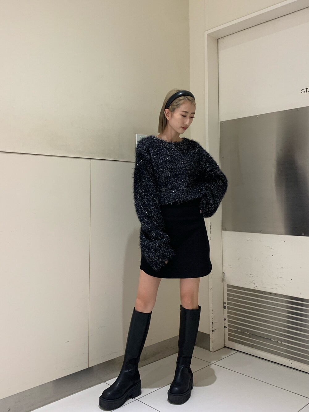 ブラック系のニット/セーター、ブラック系のスカート、ブラック系のブーツを着用したレディースの秋コーディネートの1枚目の写真