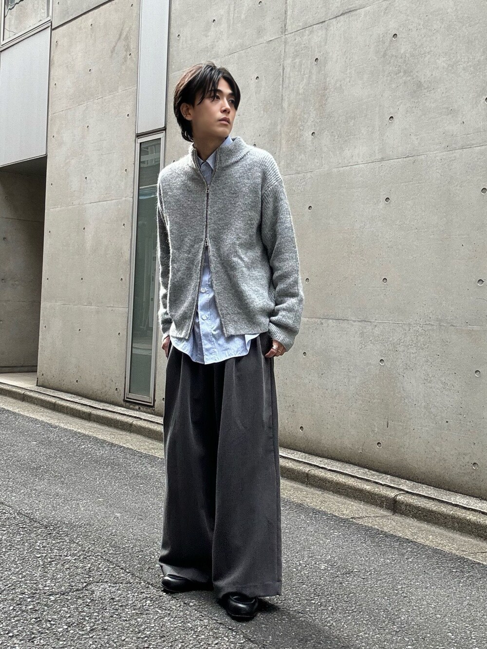 グレー系のニット/セーター、ブルー系のシャツ/ブラウス、グレー系のスラックスを着用したメンズの秋コーディネートの1枚目の写真