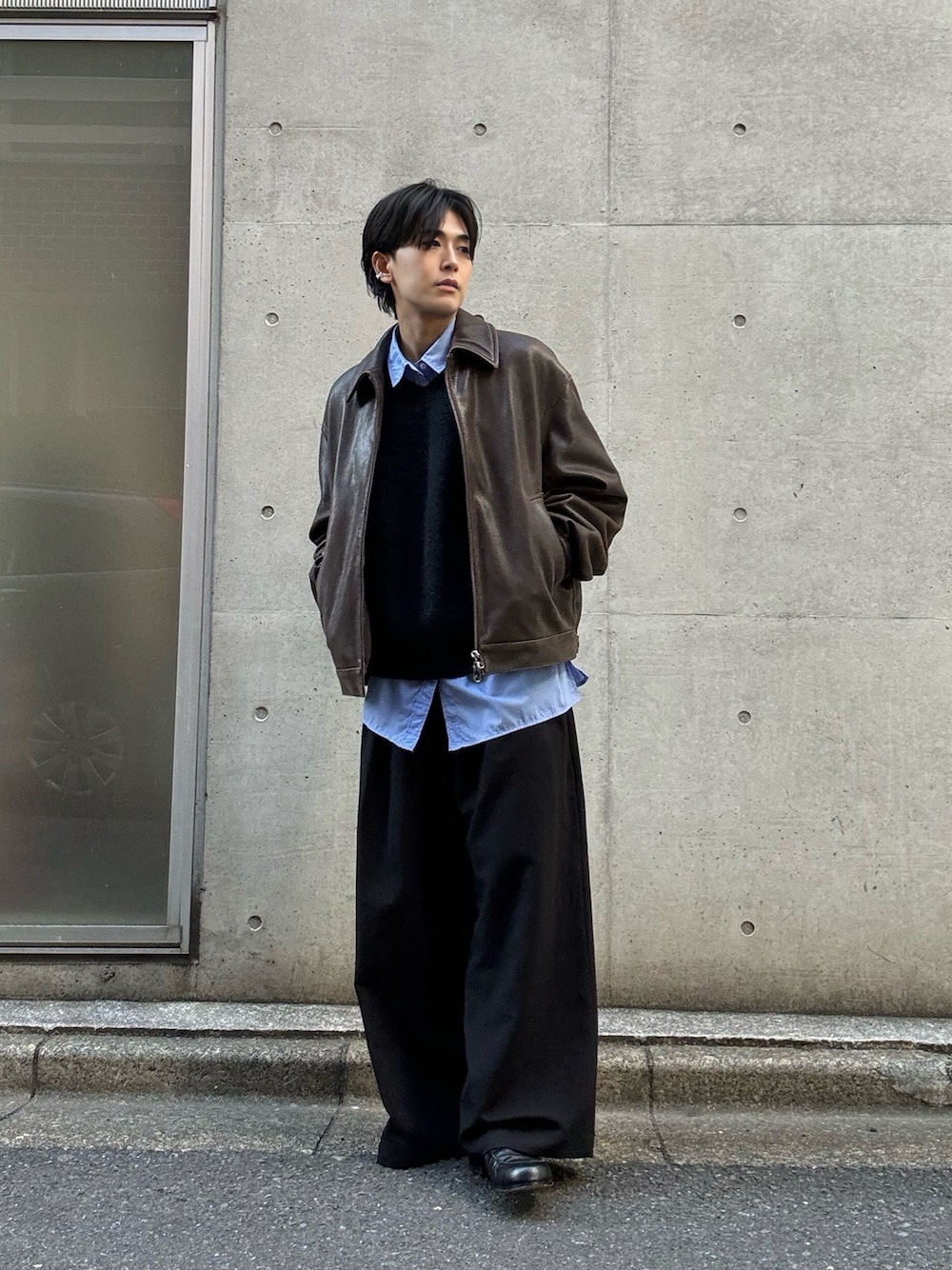 ブラック系のニット/セーター、ブルー系のシャツ/ブラウス、ブラック系のスラックスを着用したメンズの冬コーディネートの1枚目の写真