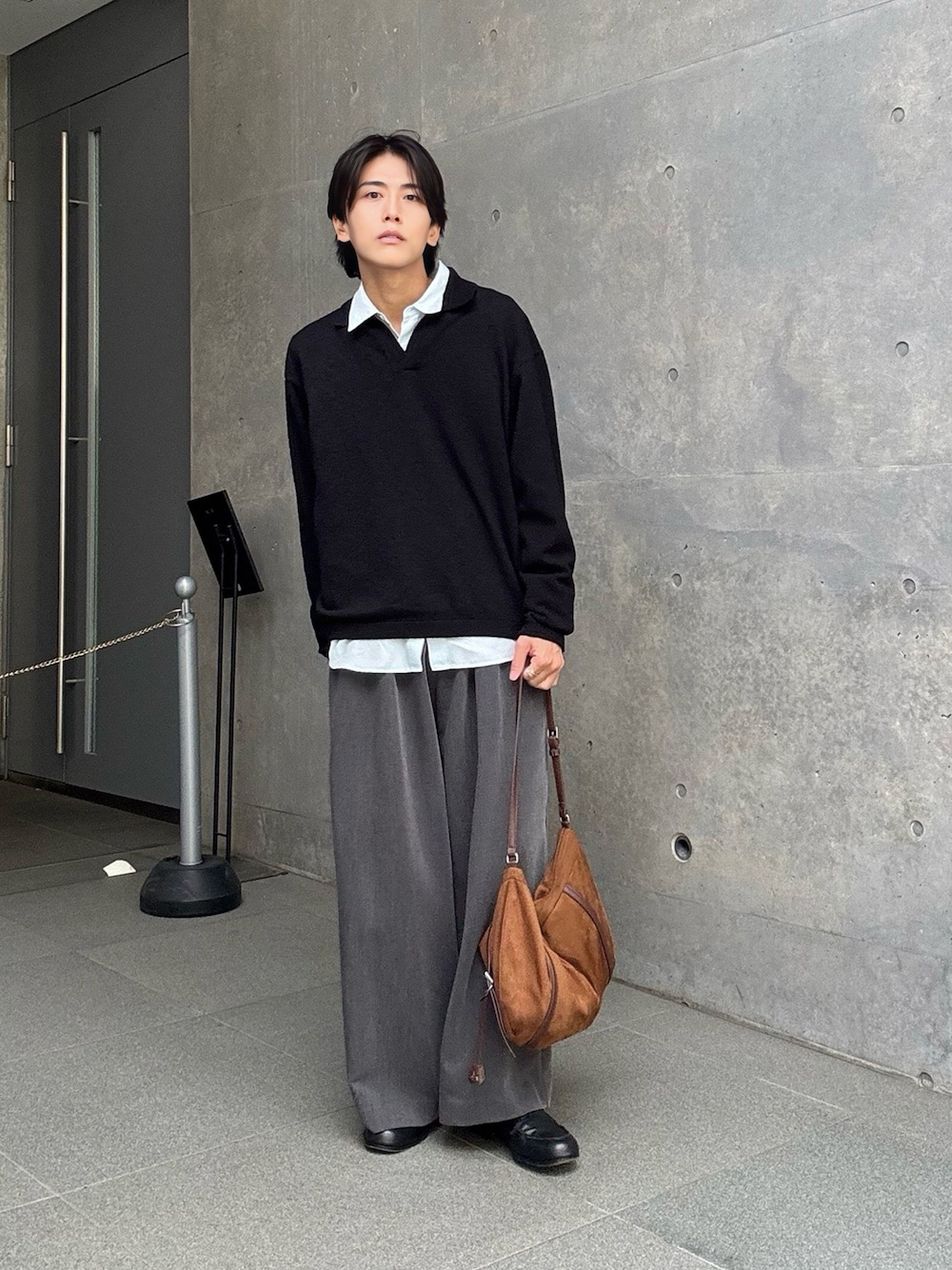 ブラック系のニット/セーター、ブルー系のシャツ/ブラウス、グレー系のスラックスを着用したメンズの春コーディネートの1枚目の写真