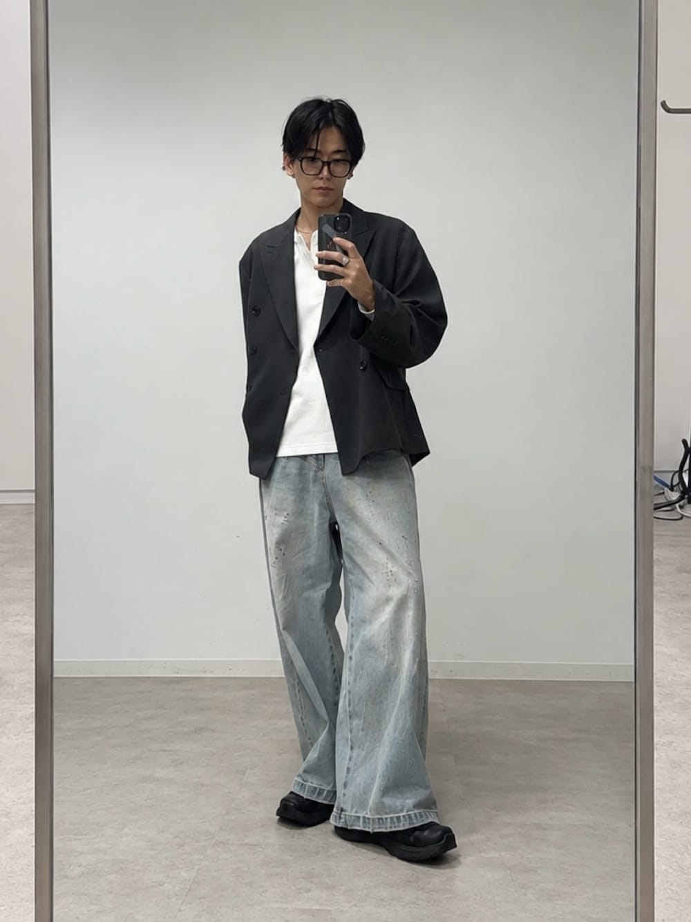 グレー系のテーラードジャケット、ブルー系のデニムパンツ、ブラック系のスニーカーを着用したメンズの秋コーディネートの1枚目の写真