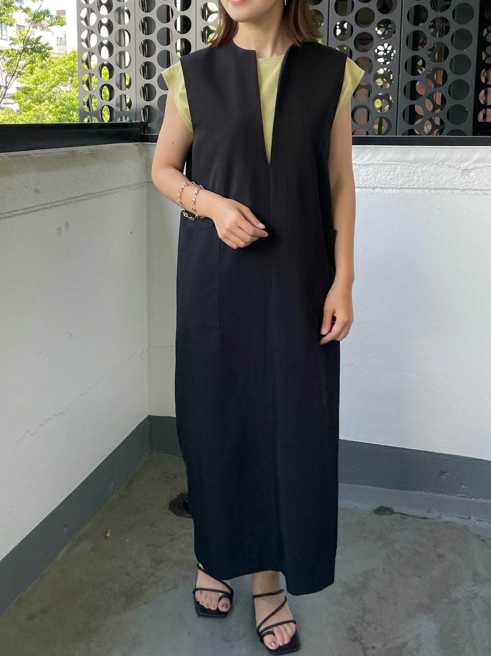 グレー系のジャンパースカート、ホワイト系のサンダルを着用したレディースの夏コーディネートの1枚目の写真