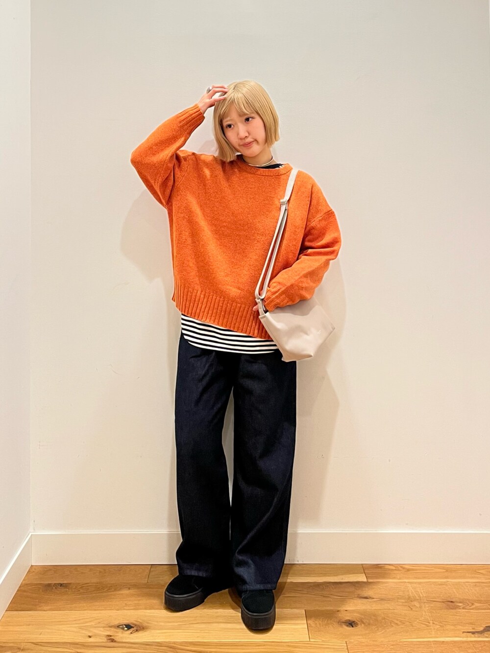 オレンジ系のニット/セーター、ブルー系のデニムパンツ、ホワイト系のTシャツ/カットソーを着用したレディースの冬コーディネートの1枚目の写真