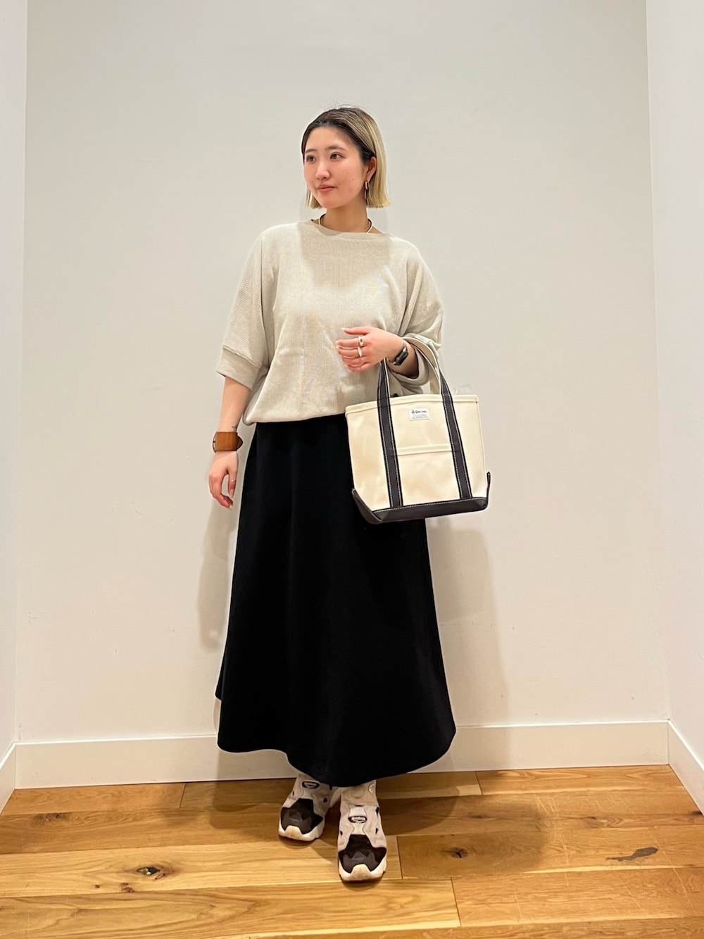 ベージュ系のTシャツ/カットソー、ブラック系のスカートを着用したレディースの春コーディネートの1枚目の写真