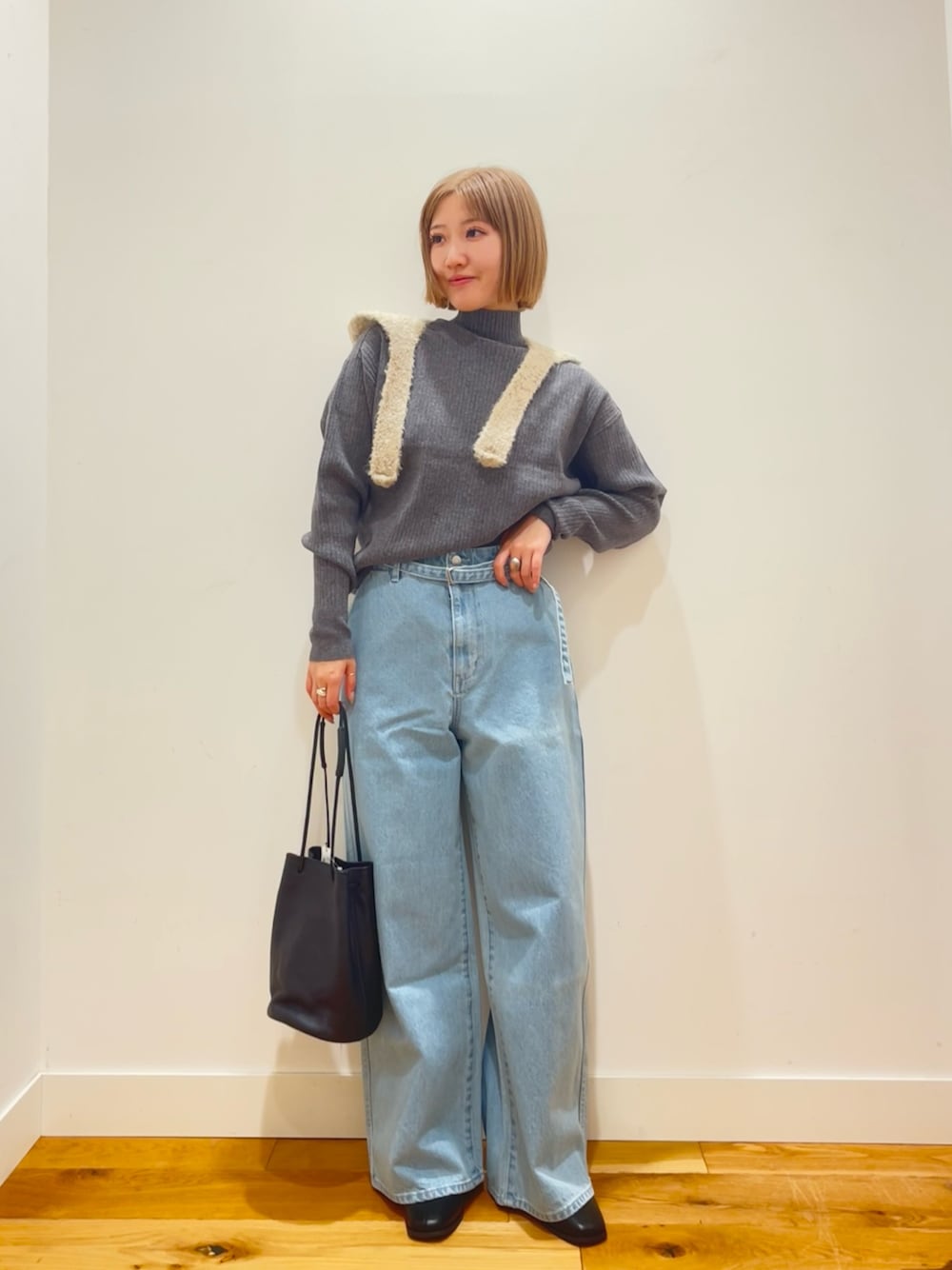 グレー系のニット/セーター、ブルー系のデニムパンツ、ブラック系のショルダーバッグを着用したレディースの冬コーディネートの1枚目の写真