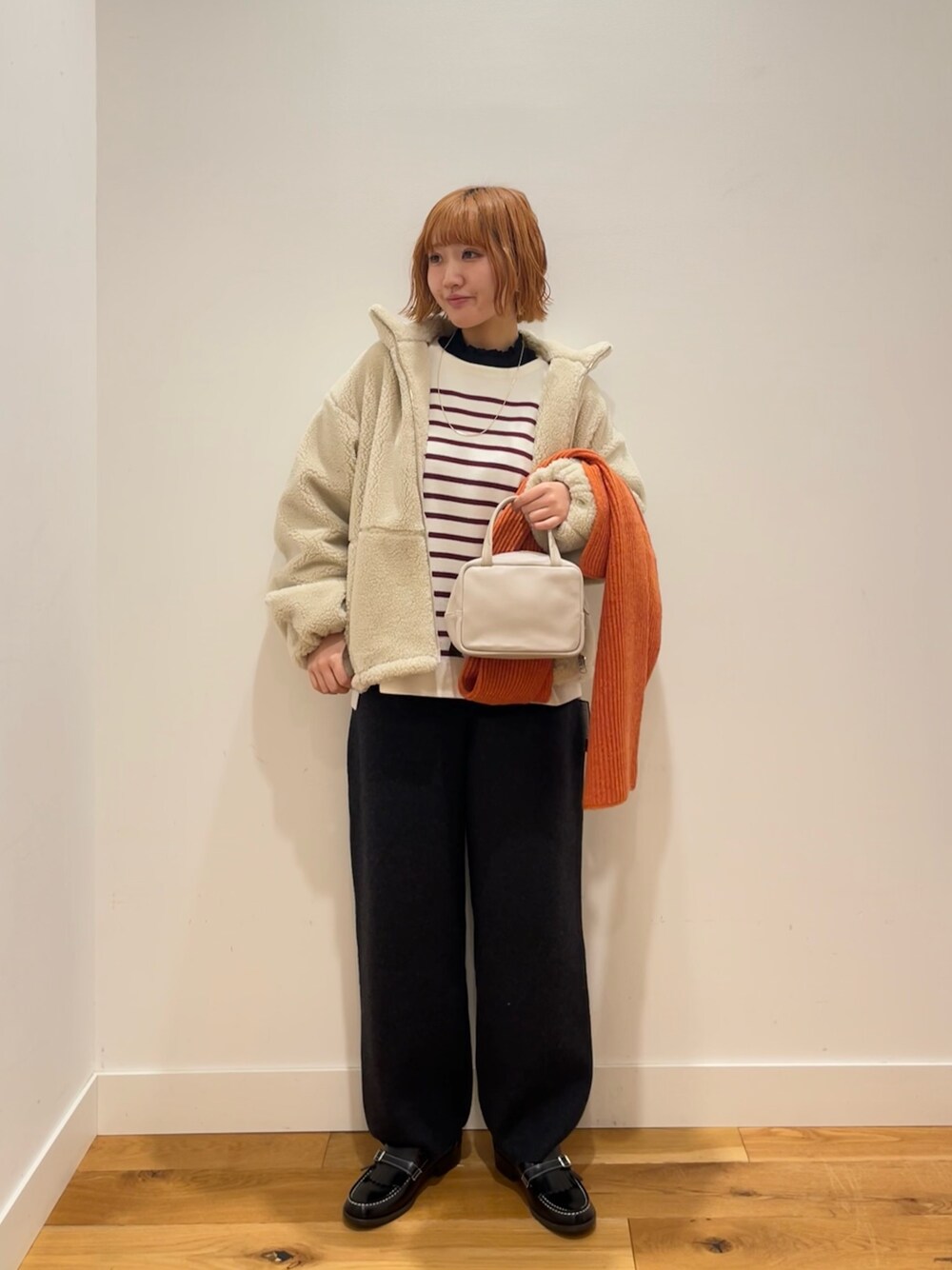 グレー系のボストンバッグ、レッド系のニット/セーター、ホワイト系のその他アウターを着用したレディースの冬コーディネートの1枚目の写真