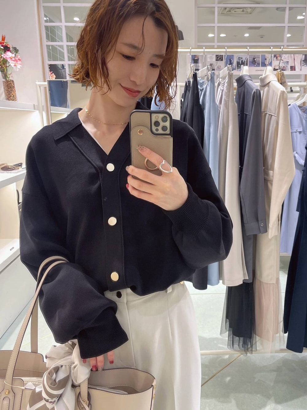 ブラック系のニット/セーター、ホワイト系のトートバッグ、ベージュ系のスラックスを着用したレディースの冬コーディネートの1枚目の写真