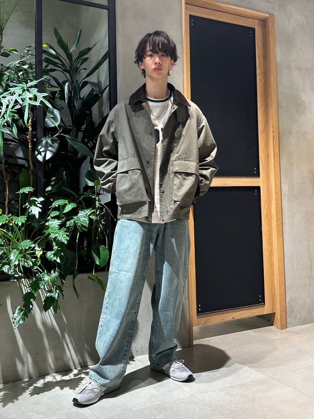 グレー系のスニーカー、ブルー系のデニムパンツ、グリーン系のブルゾンを着用したメンズの秋コーディネートの1枚目の写真