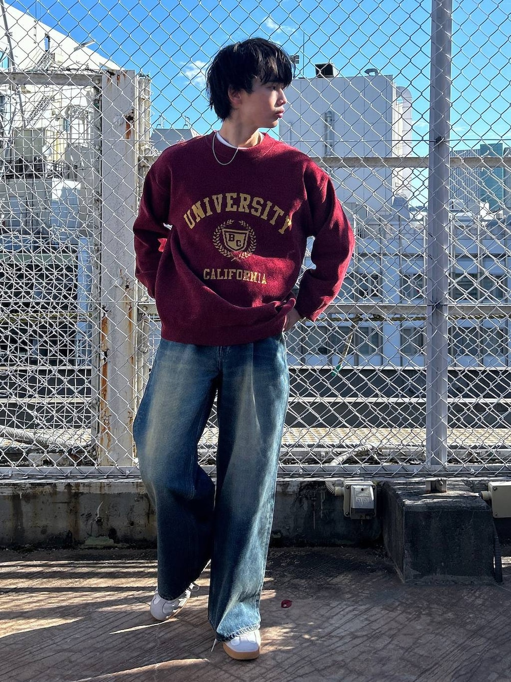 レッド系のニット/セーター、ホワイト系のTシャツ/カットソー、ブルー系のデニムパンツを着用したメンズの冬コーディネートの1枚目の写真