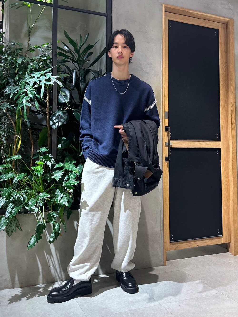 ブラック系のドレスシューズ、ブルー系のニット/セーター、ホワイト系のTシャツ/カットソーを着用したメンズの秋コーディネートの1枚目の写真