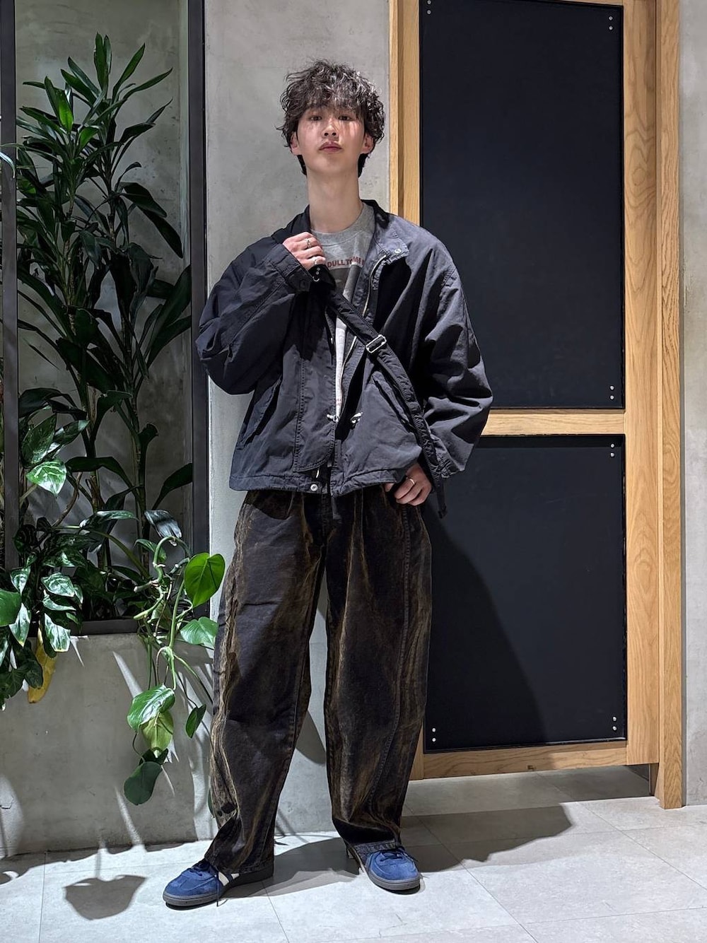 ブラック系のショルダーバッグ、ブラック系のモッズコート、ブルー系のスニーカーを着用したメンズの春コーディネートの1枚目の写真