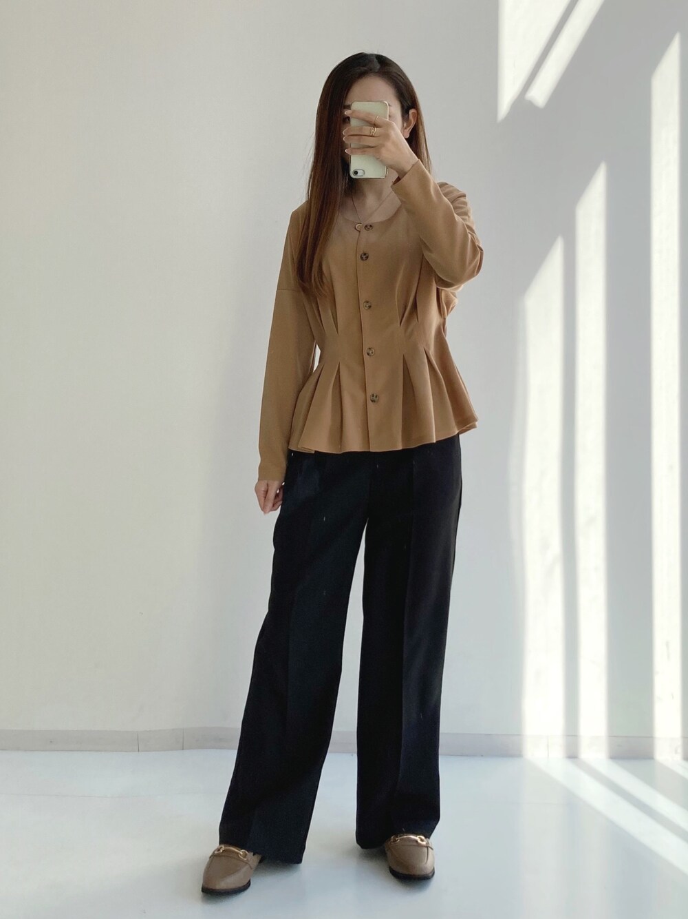 ブラック系のスラックス、ベージュ系のシャツ/ブラウス、ベージュ系のローファーを着用したレディースの冬コーディネートの1枚目の写真