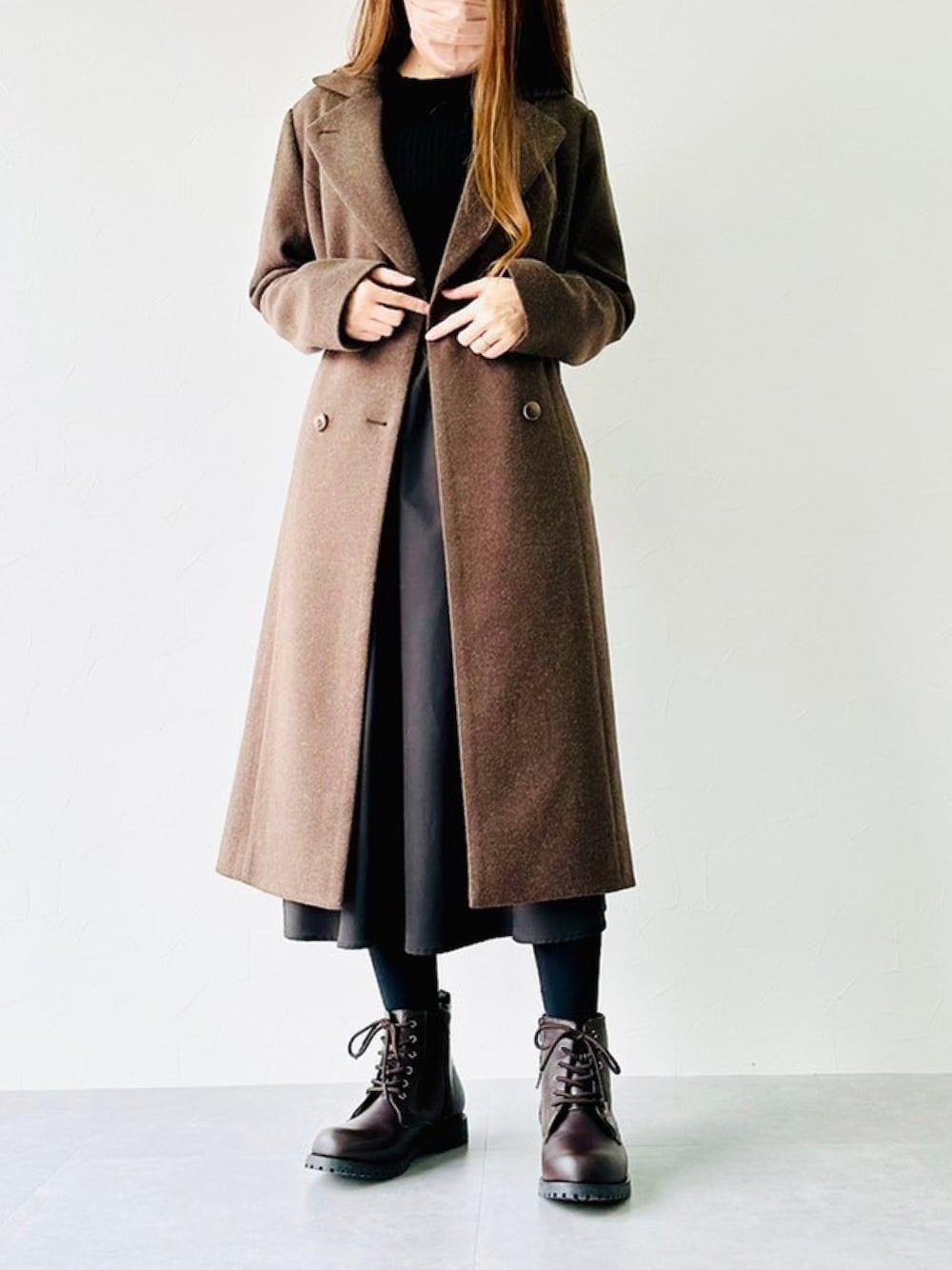 ブラウン系のチェスターコート、ブラック系のワンピース、ブラウン系のブーツを着用したレディースの冬コーディネートの1枚目の写真