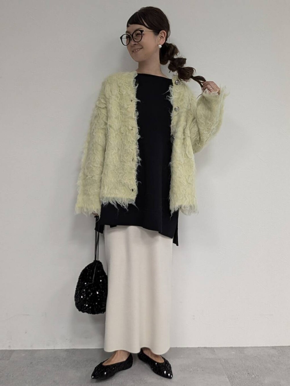 ブラック系のパンプス、ブラック系のショルダーバッグ、ホワイト系のスカートを着用したレディースの秋コーディネートの1枚目の写真