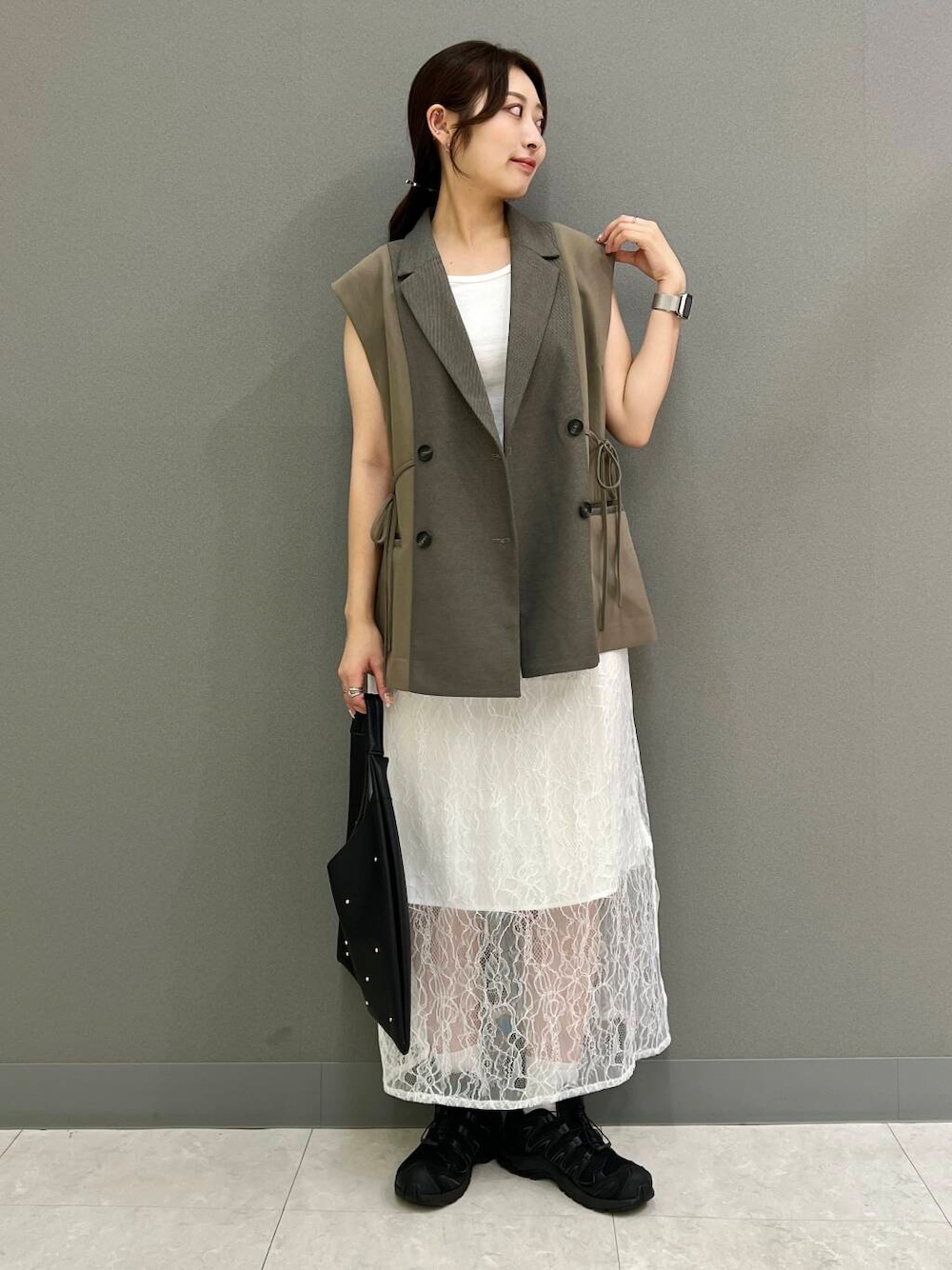 ブラック系のトートバッグ、ホワイト系のTシャツ/カットソー、ブラウン系のベストを着用したレディースの秋コーディネートの1枚目の写真