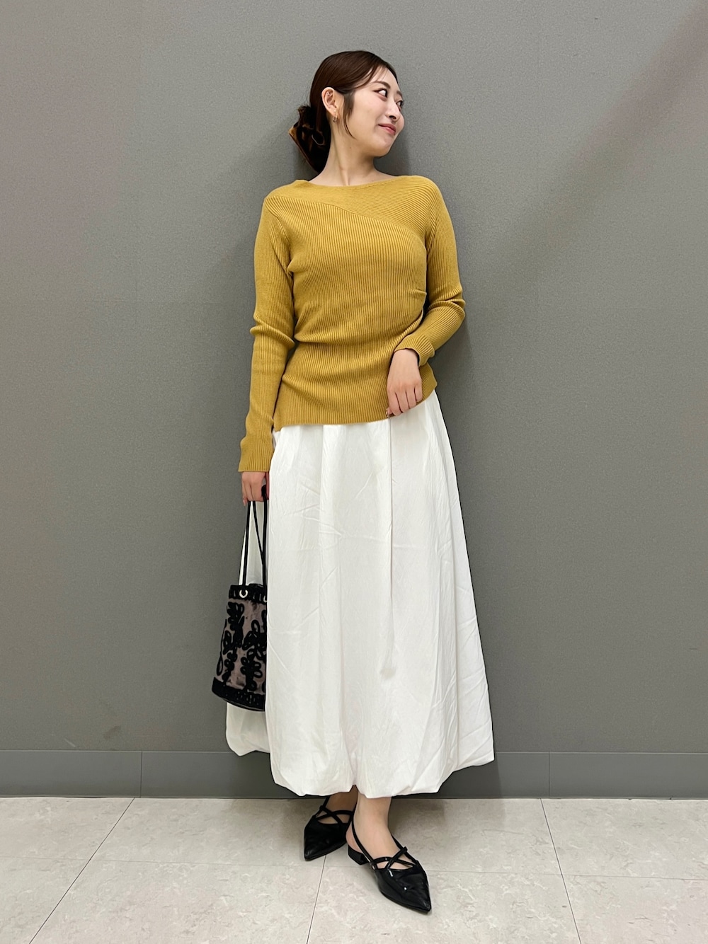 イエロー系のニット/セーター、ホワイト系のスカート、ブラック系のその他シューズを着用したレディースの秋コーディネートの1枚目の写真